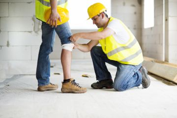 a contractor wrapping a colleagues knee after an accident